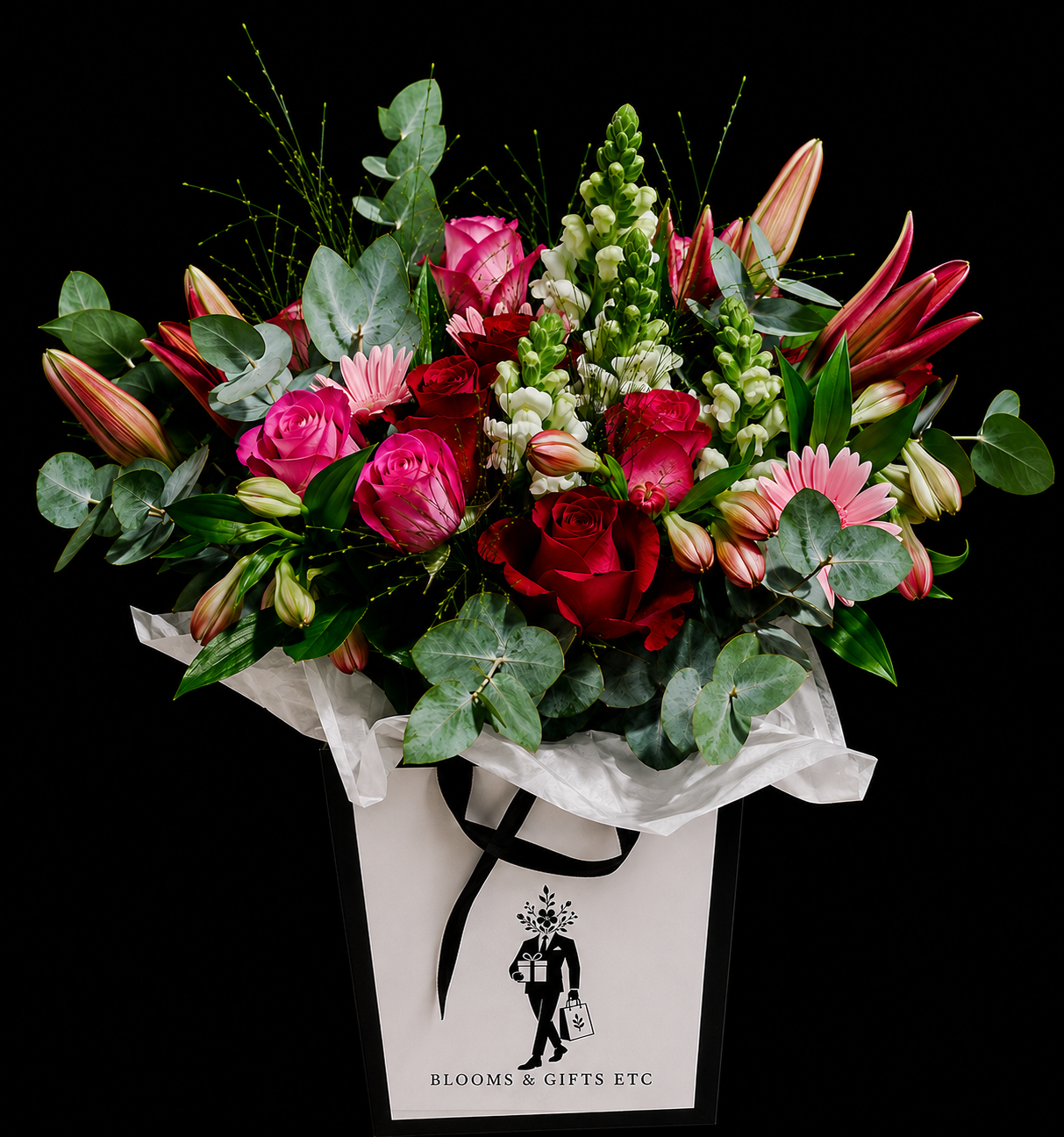 Bouquet of flowers made of pink roses, red roses, white snapdragons, pink gerberas, pink alstromerias, red asiatic lilies, pennygum and greenery in a white    branded gift bag by Blooms Gifts Etcetera