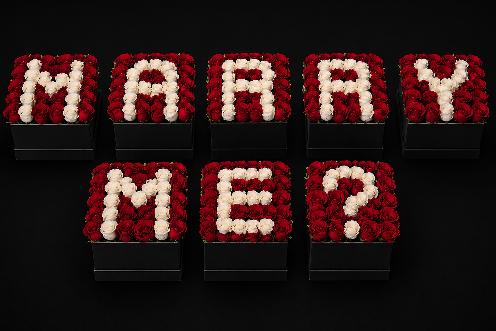 Red and white roses arranged in 8  square black gift boxes spelling 'MARRY ME?' on a black background